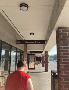 Photo shows Kyle walking at the Hannaford shopping plaza. You can see signs for Bruegger's Bagels and Capitol Cleaners. The stores are located right next to each other.