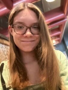 Photo shows a woman with long hair and glasses smiling for the camera 