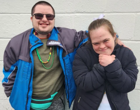 Bean (left) poses for a photo with his friend of four years Beth (right). Bean has his arm around Beth's shoulder and Beth's hands are clasped under her chin. Both are smiling.