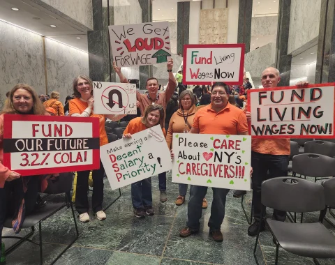 Seven Living Resources team members pose for a photo. They are holding up rally signs.