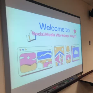 A projector screen displays a presentation that says Welcome to Social Media Workshop Day 2