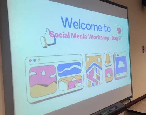 A projector screen displays a presentation that says Welcome to Social Media Workshop Day 2