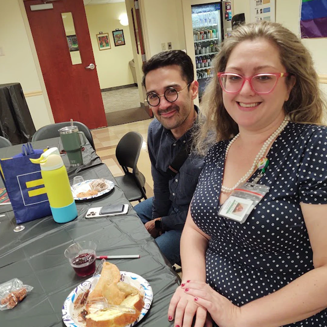 A woman and a man in glasses smile at the camera.