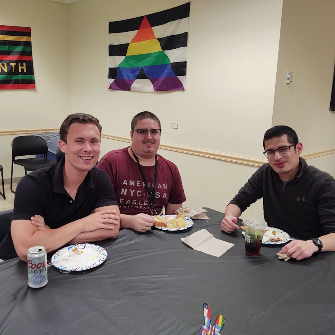 Three men sit at a table and smile at the camera.