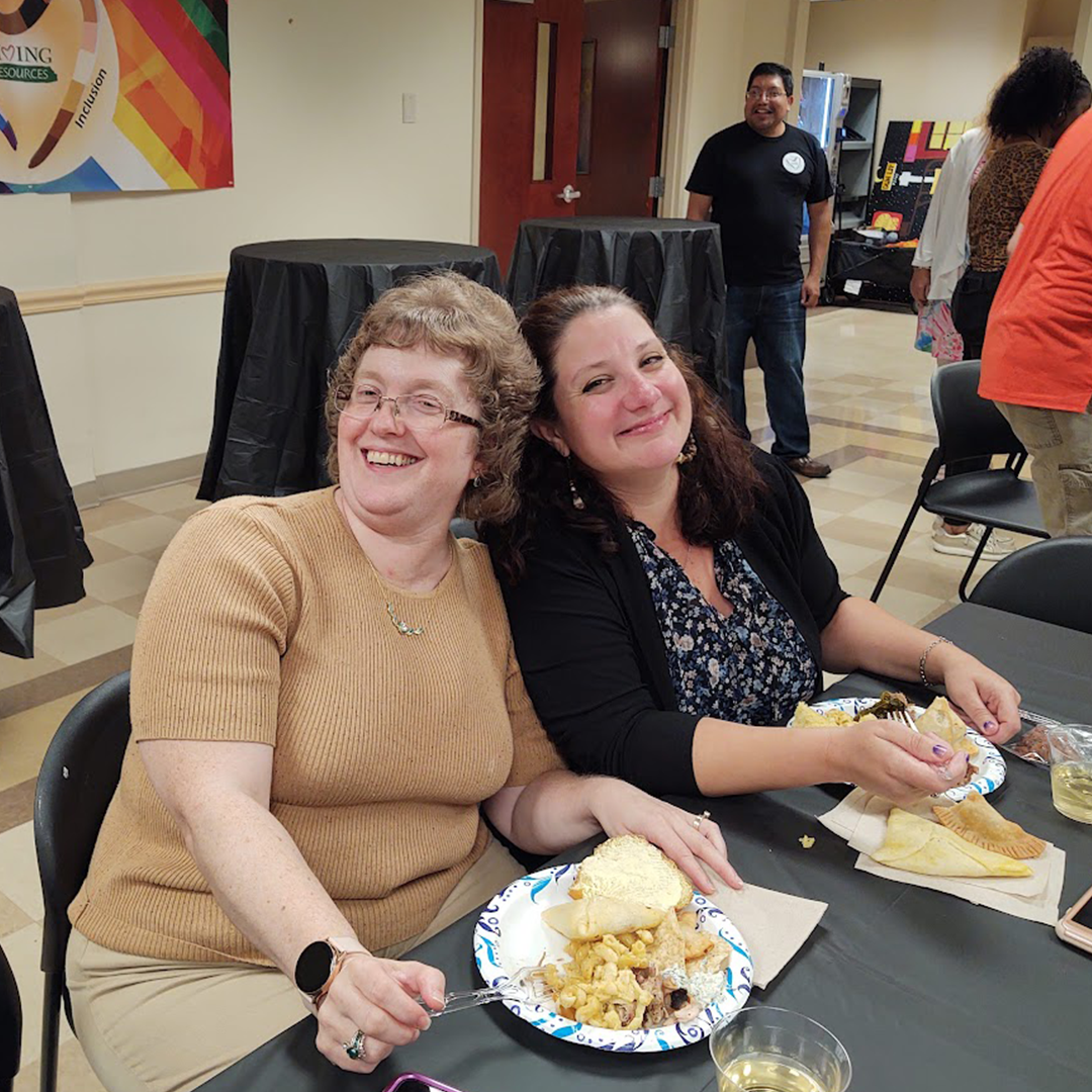 Two women sitting at a table smile for the camera