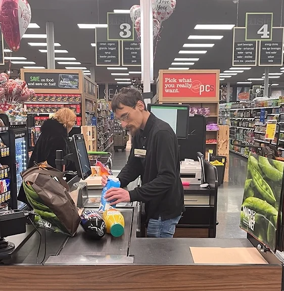 A man cashes out a customer at a grocery store.