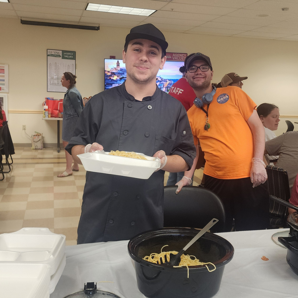 1 A student in the college experience program serves spaghetti at a fundraiser.