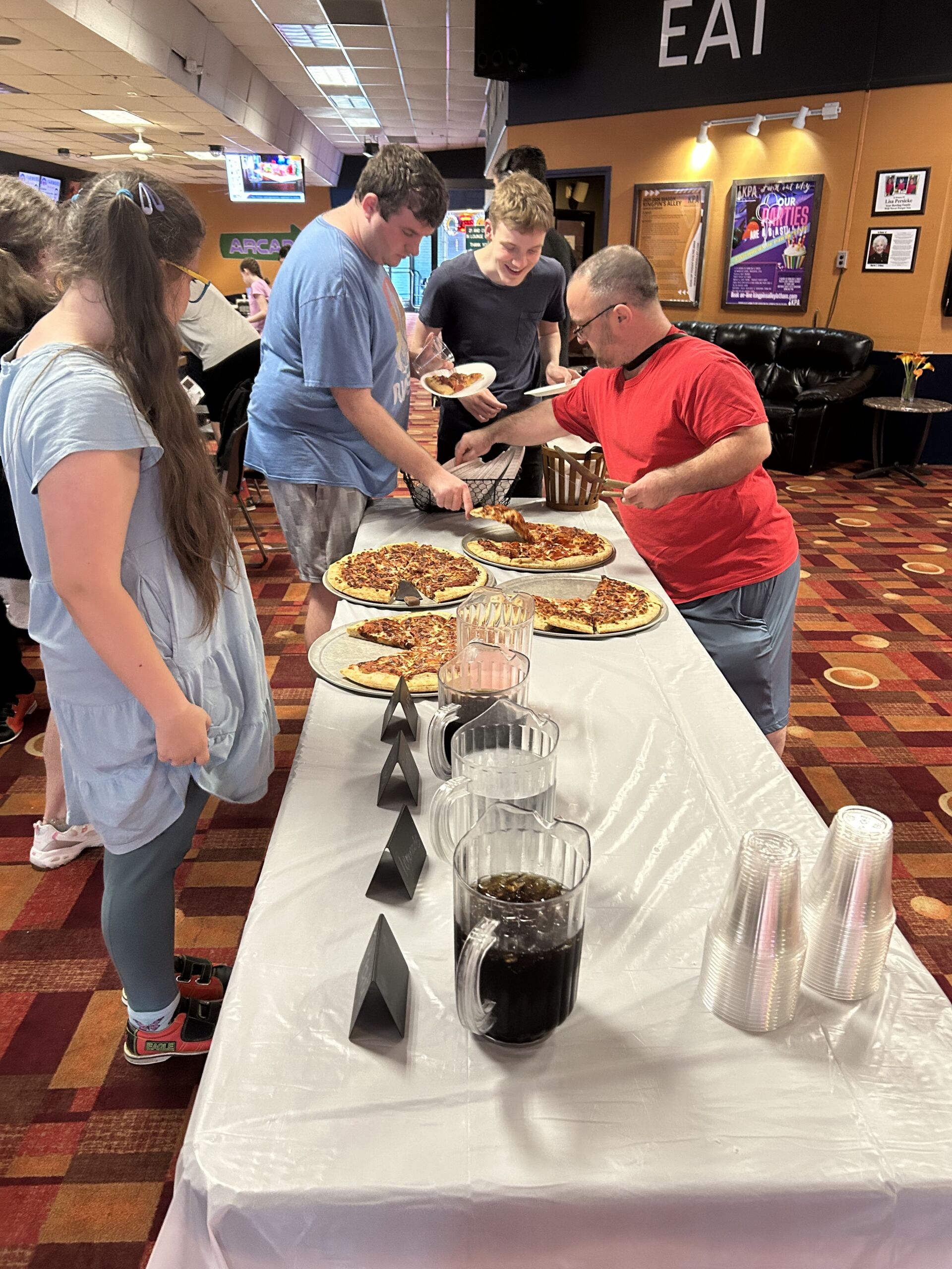 IMG_2047 Students in living resources after school program gather at a table of pizza to select their slice.