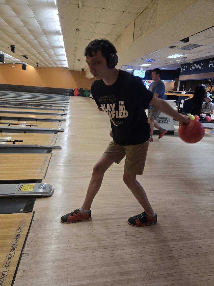 image000003 A young man wearing headphones gets ready to bowl at the end of year party.