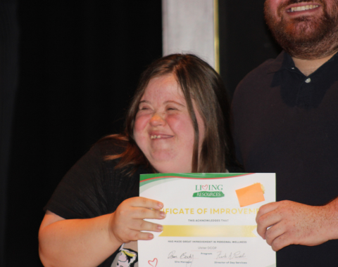 Day Services Awards 9 An individual in our day services program smiles with staff holding an award.