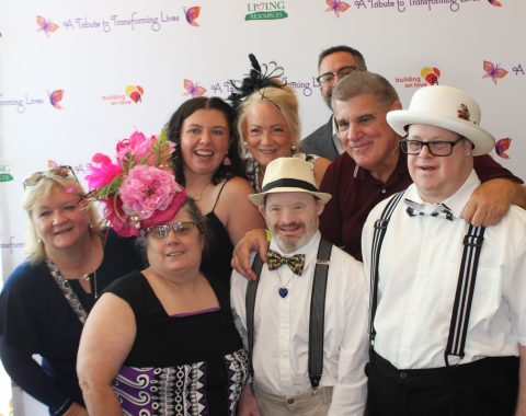 A group of people stand in front of a backdrop at a photo booth.